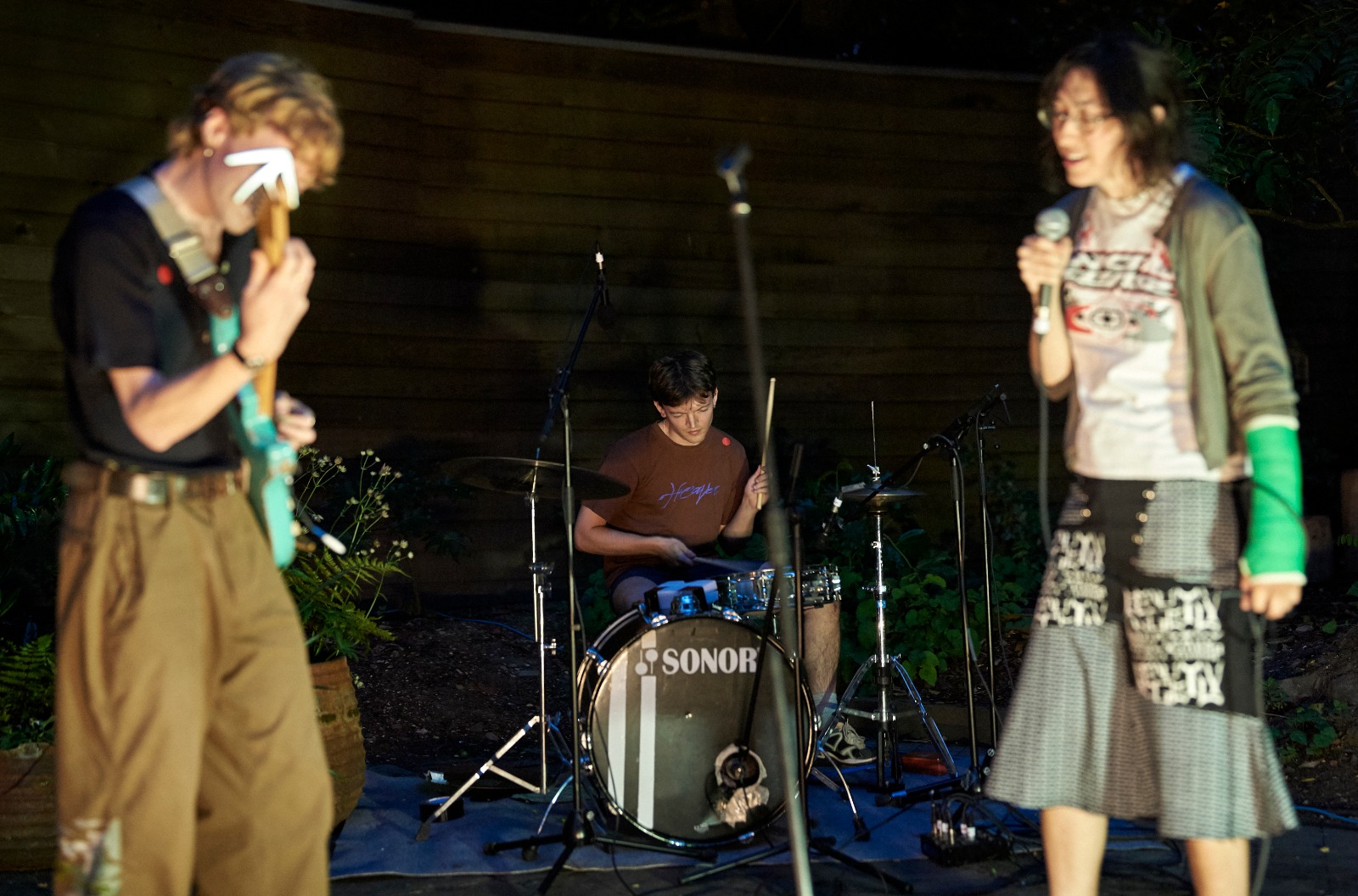Three band members outside playing music in the dark