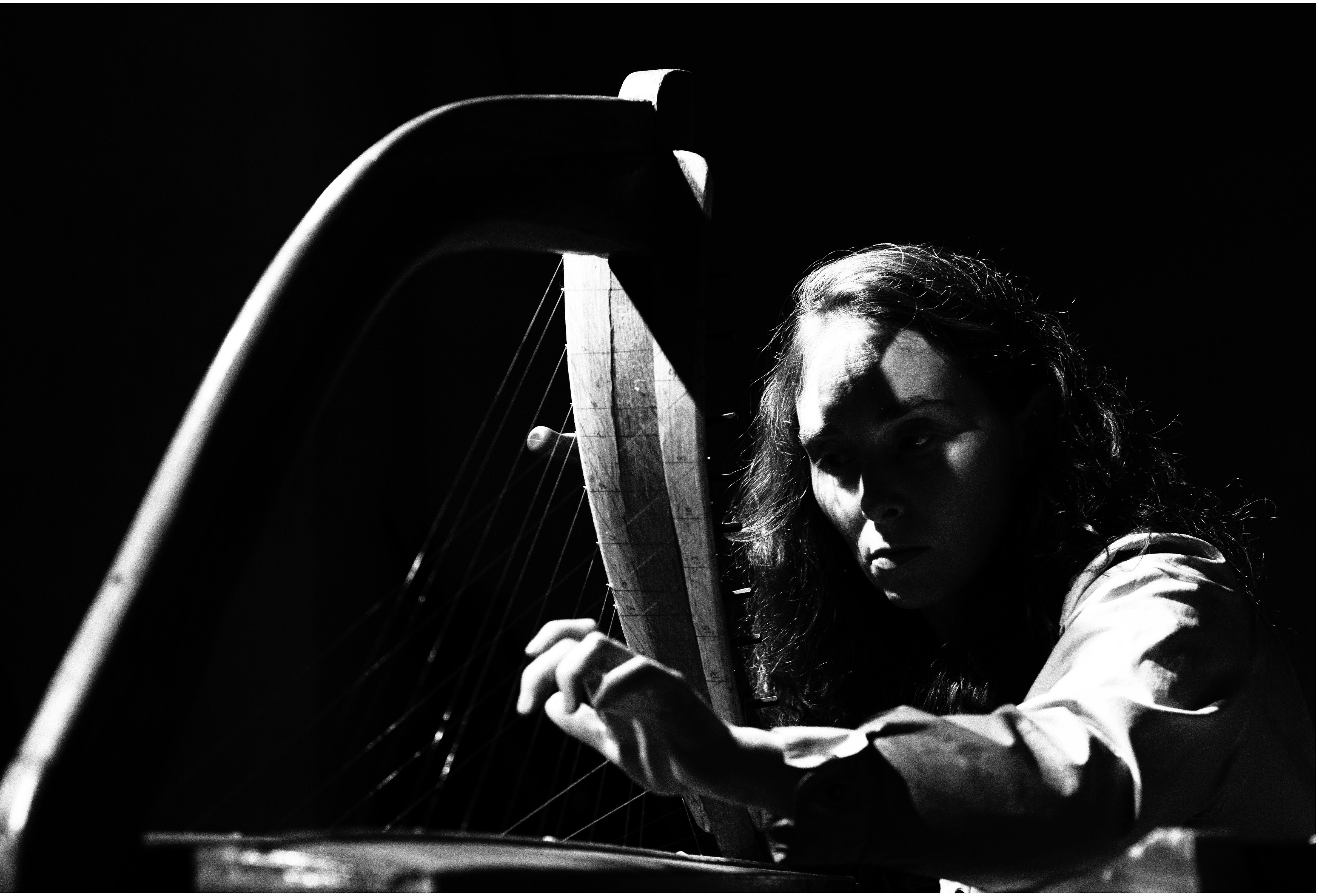 Black and white image of Aine O'Dwyer with a harp. 