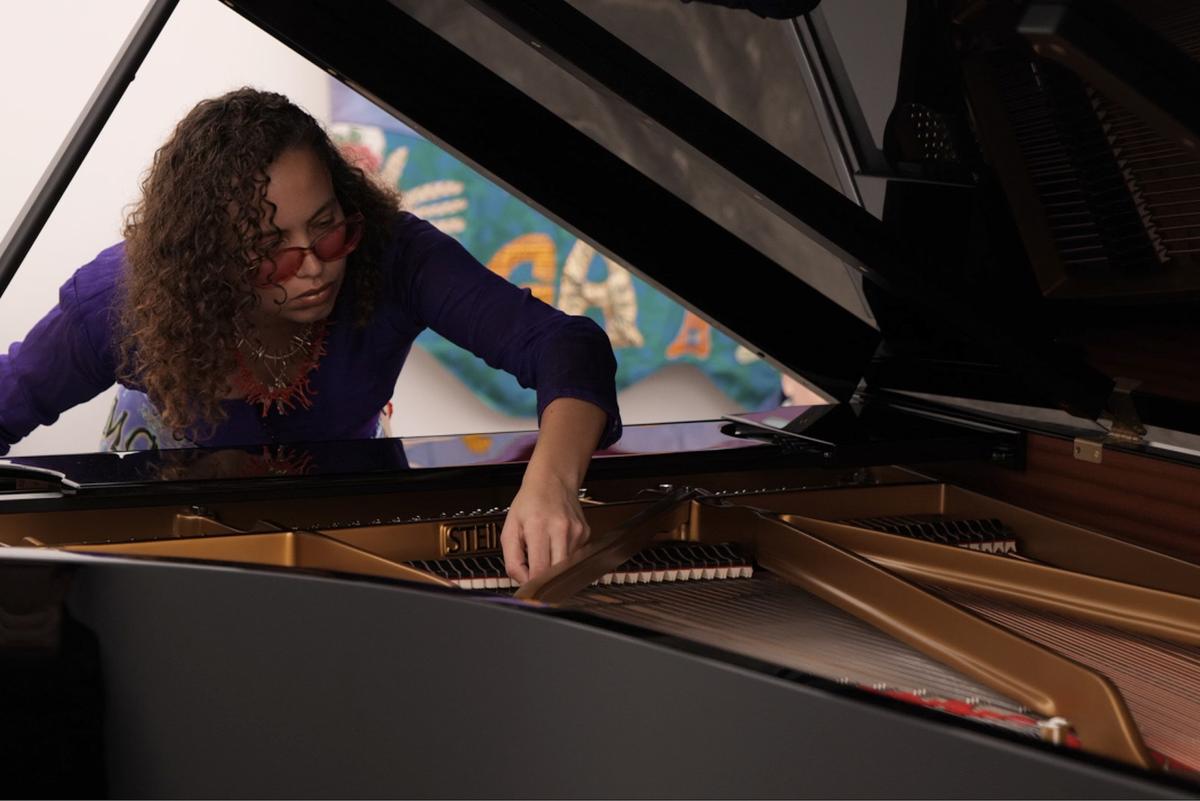 Naima Karlsson plays the strings of a piano.